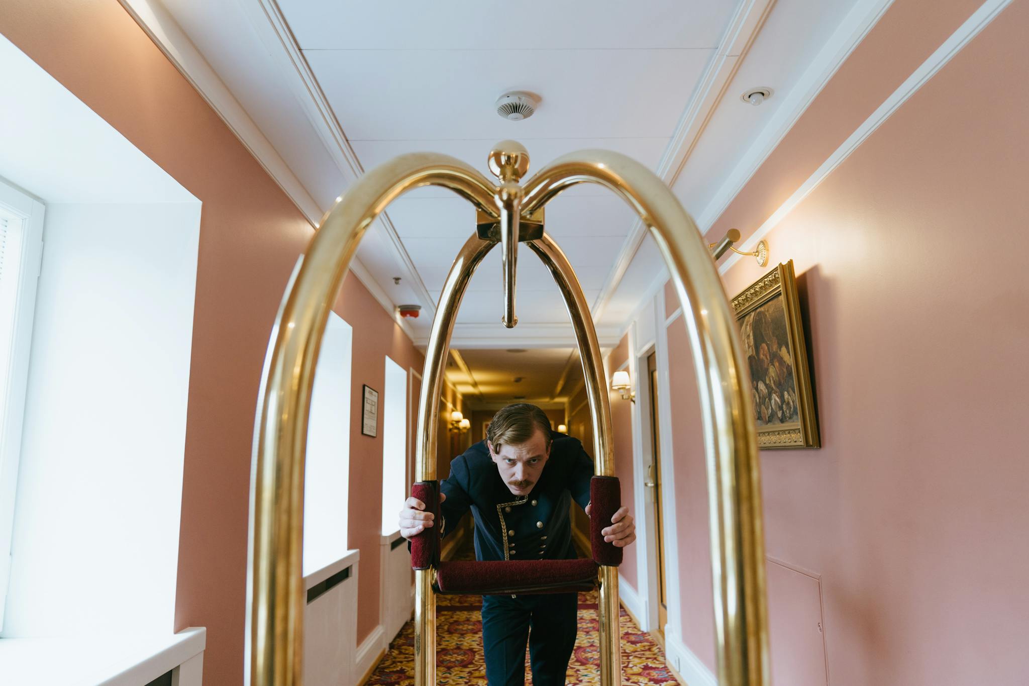 A bellboy pushes a luggage cart down a luxurious hotel corridor, embodying service and elegance.