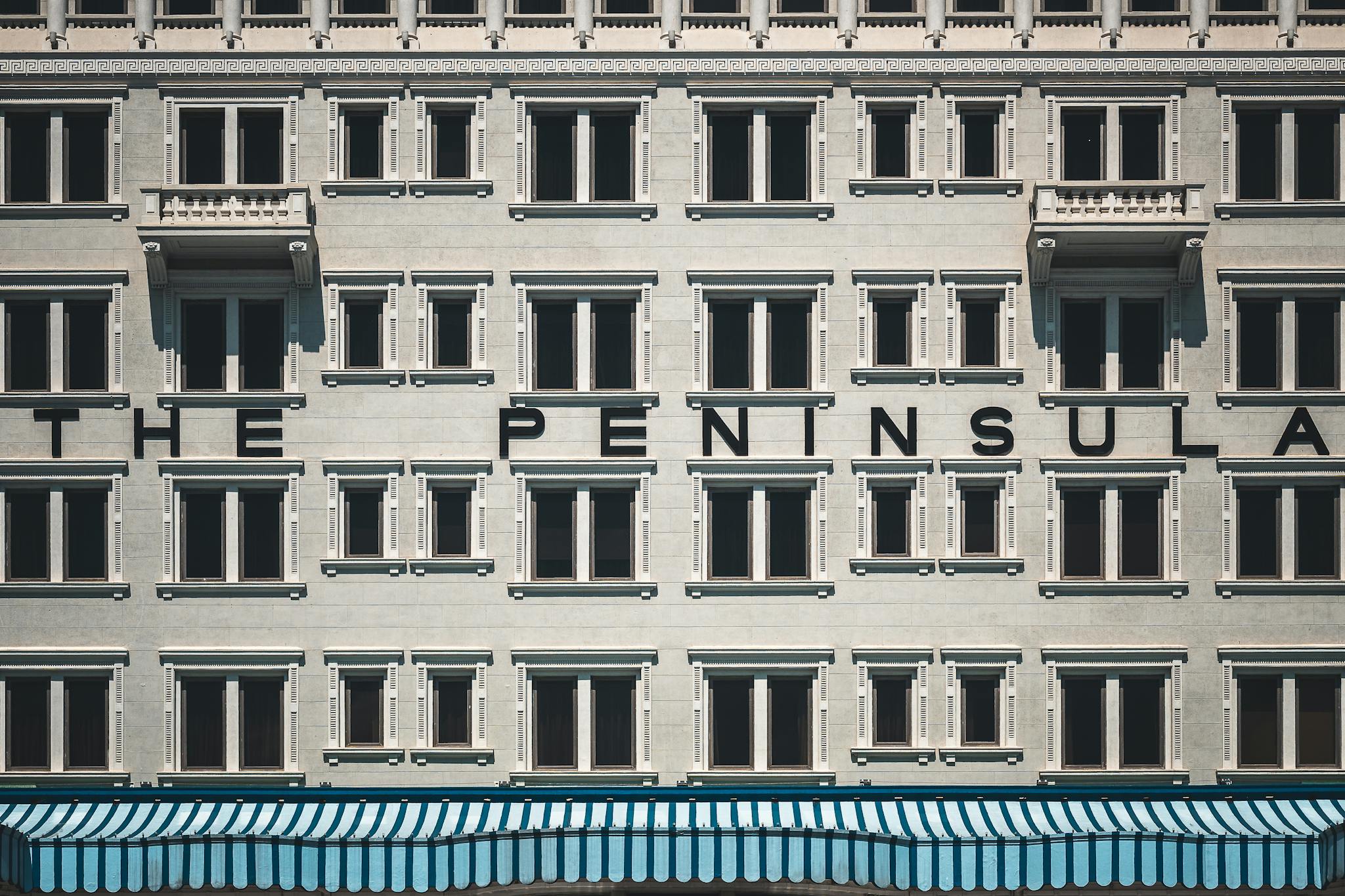 Close-up of The Peninsula Hotel facade in Hong Kong showcasing its unique architectural design.
