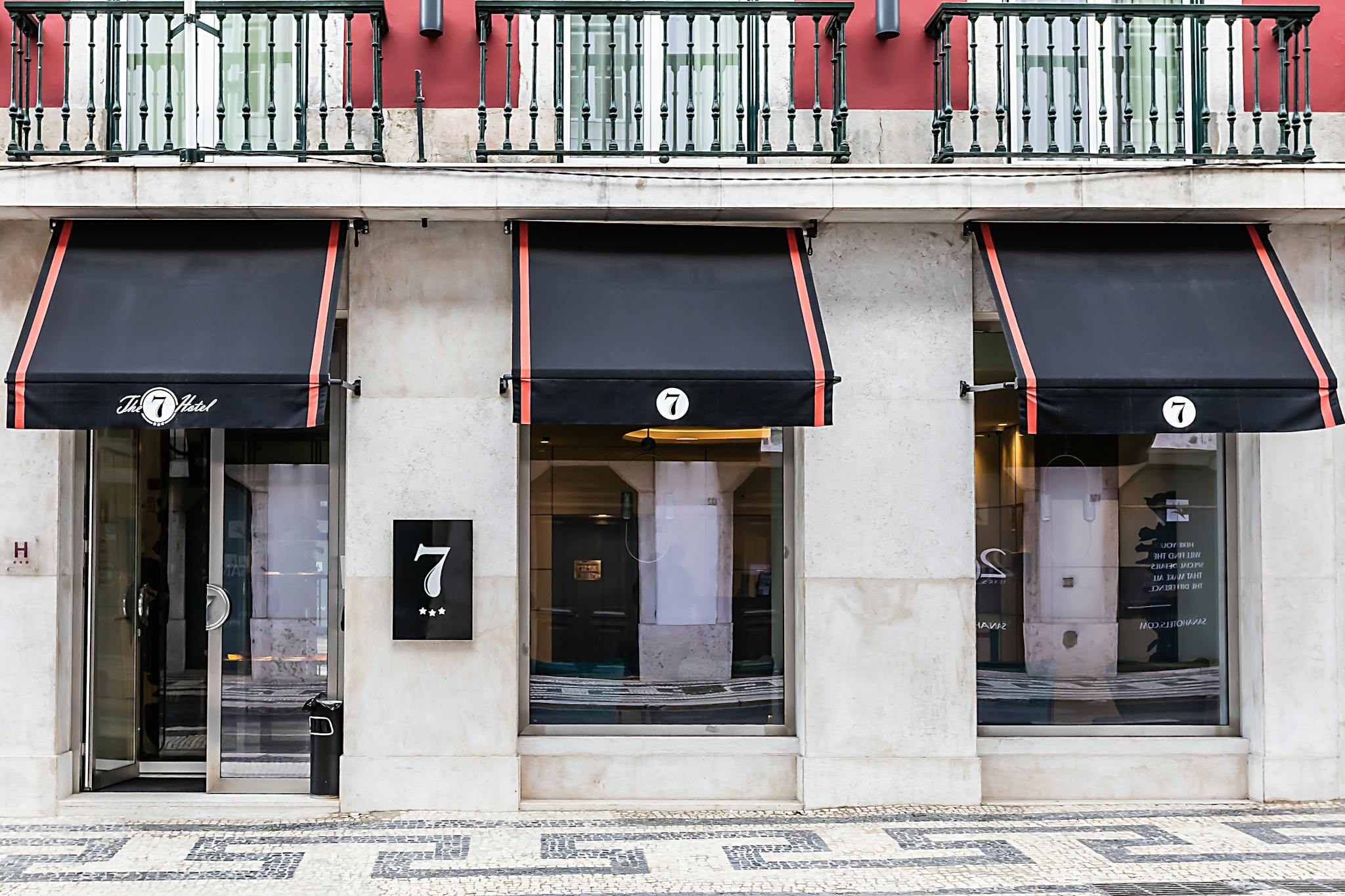 Elegant facade of The 7 Hotel with awnings and glass doors in Lisbon, Portugal.