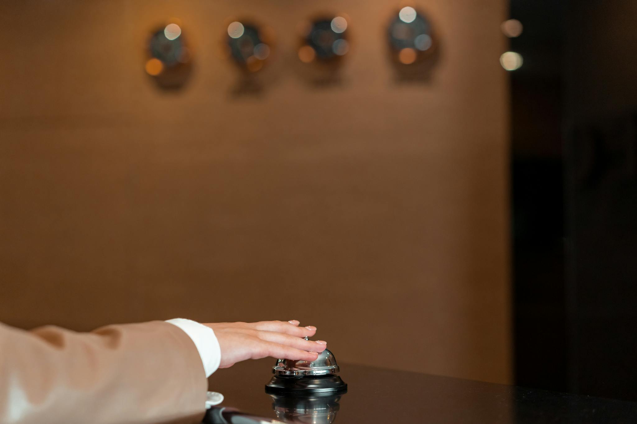 A hand pressing a bell at a hotel reception, symbolizing service and hospitality.