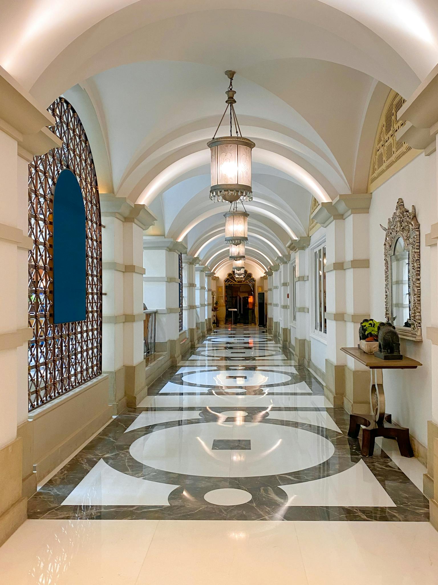 A luxurious hotel corridor featuring elegant chandeliers and intricate flooring in Mumbai, India.