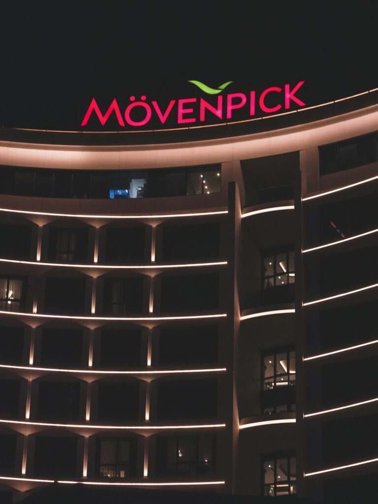 Stunning night view of Mövenpick Hotel's illuminated facade with vibrant signage.