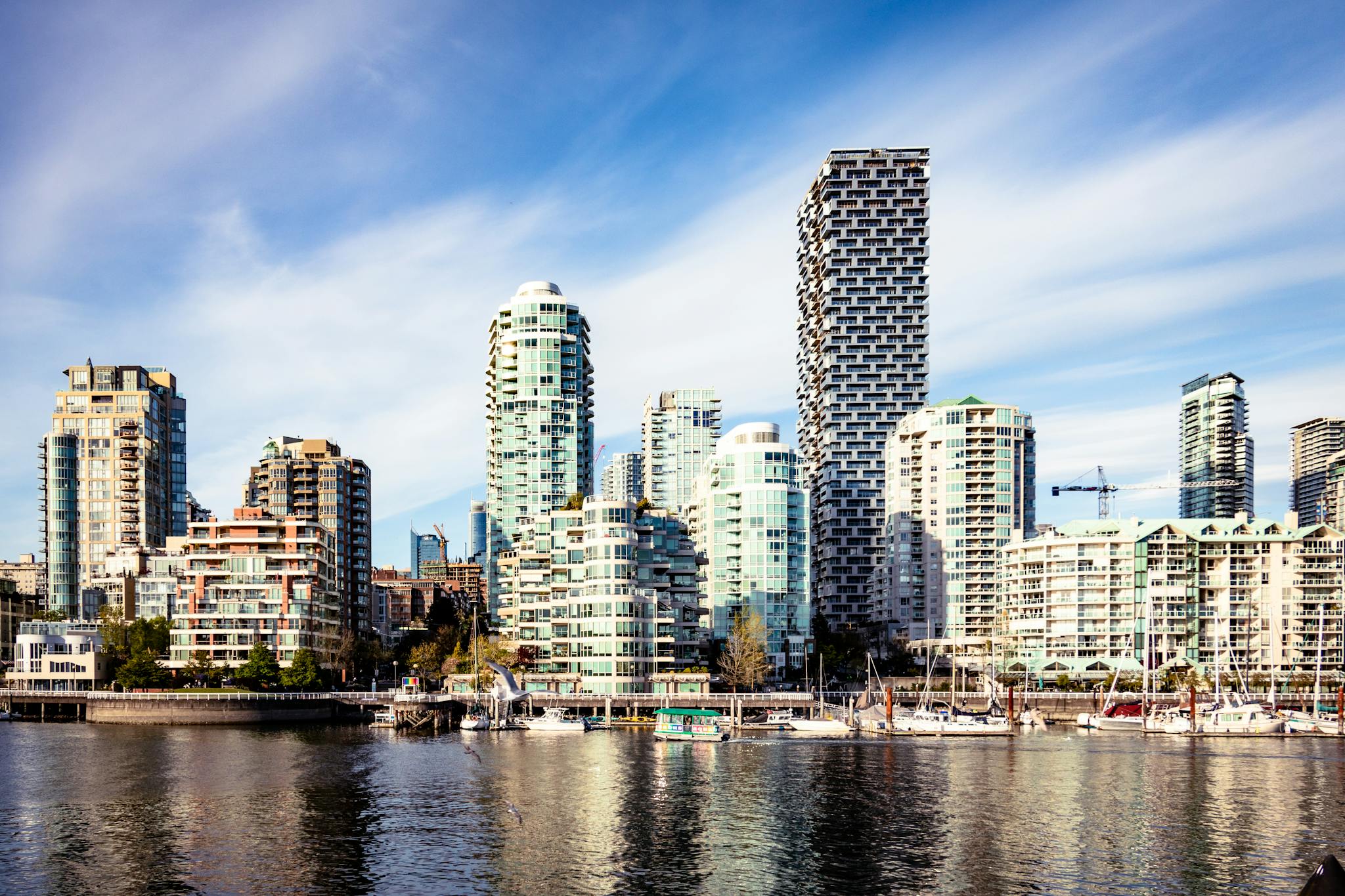 Vancouver cityscape featuring modern skyscrapers and waterfront under a blue sky.